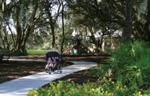 Woman pushing a stroller thru a park.
