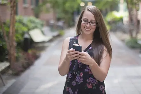 Woman walking looking at her smart phone.